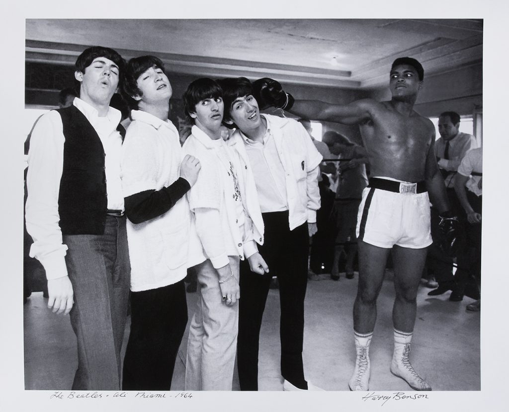 Black and white photograph of five men (The Beatles and Cassius Clay) stood together smiling at the camera