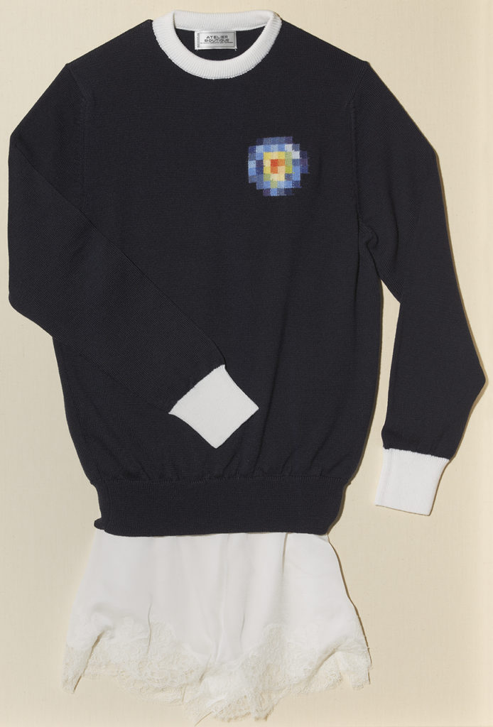Navy jumper and cream shorts. The Navy jumper has cream cuffs and a small blue and yellow embroidered logo.