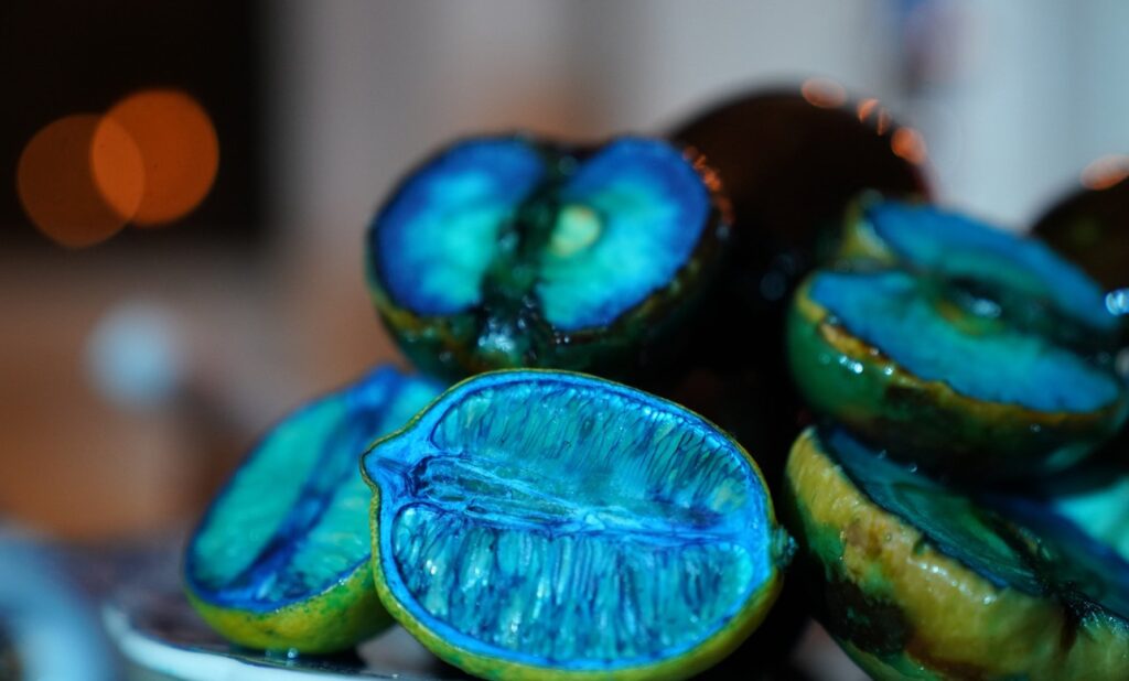 A plate of sliced lemons that have dried out and are dyed blue are stacked on top of each other. 