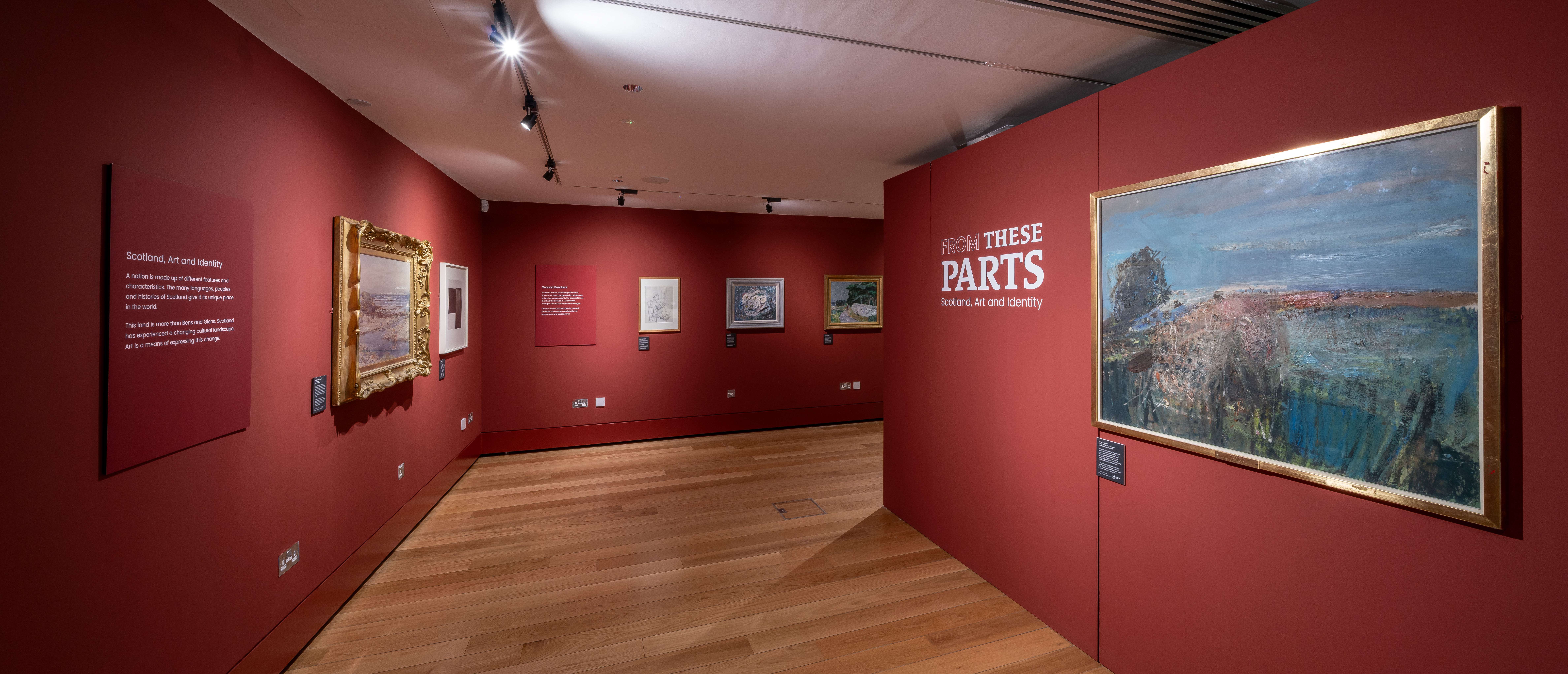 Artworks on red walls in a gallery space.