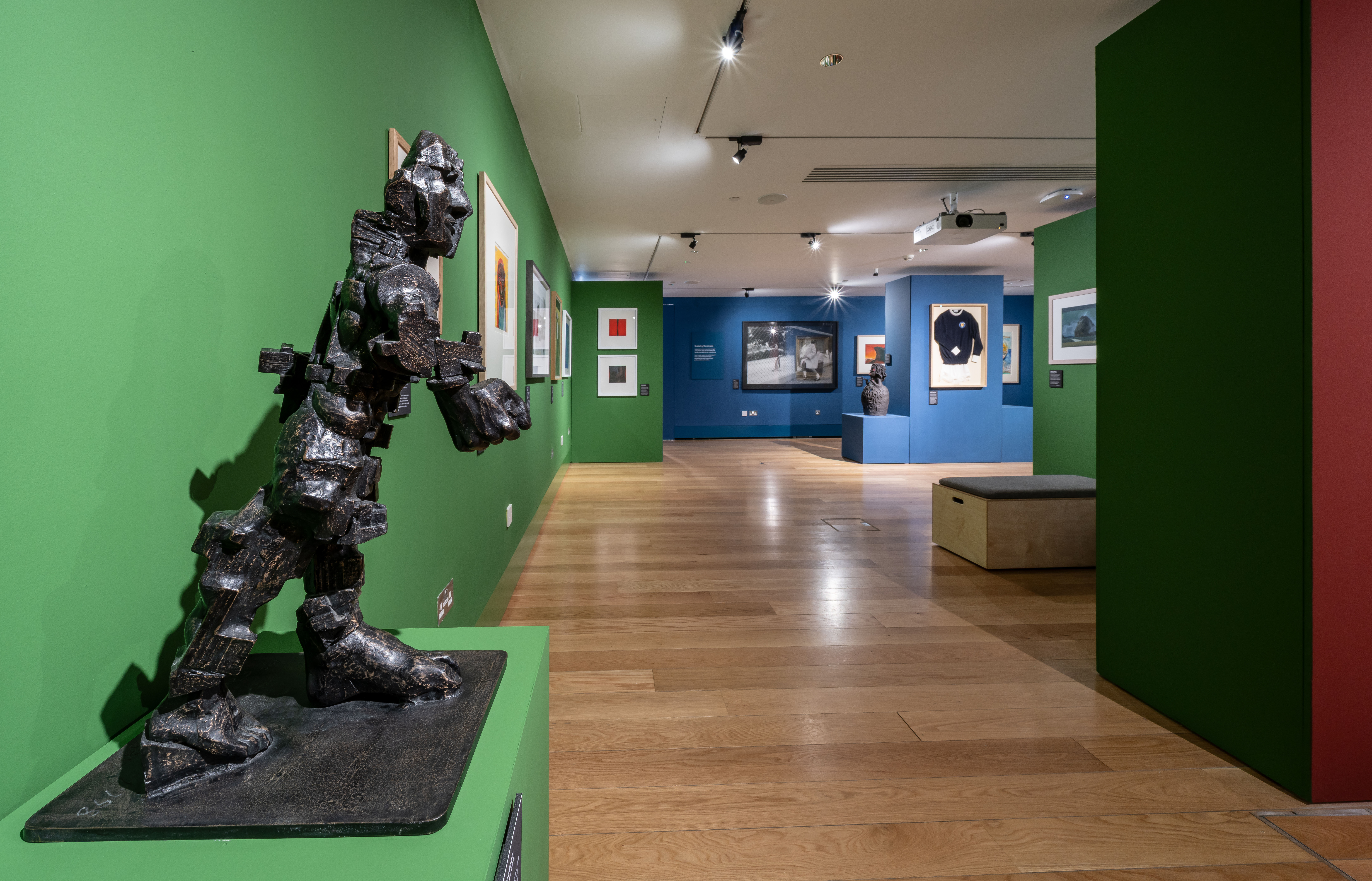 A sculpture and artworks on green and blue walls.